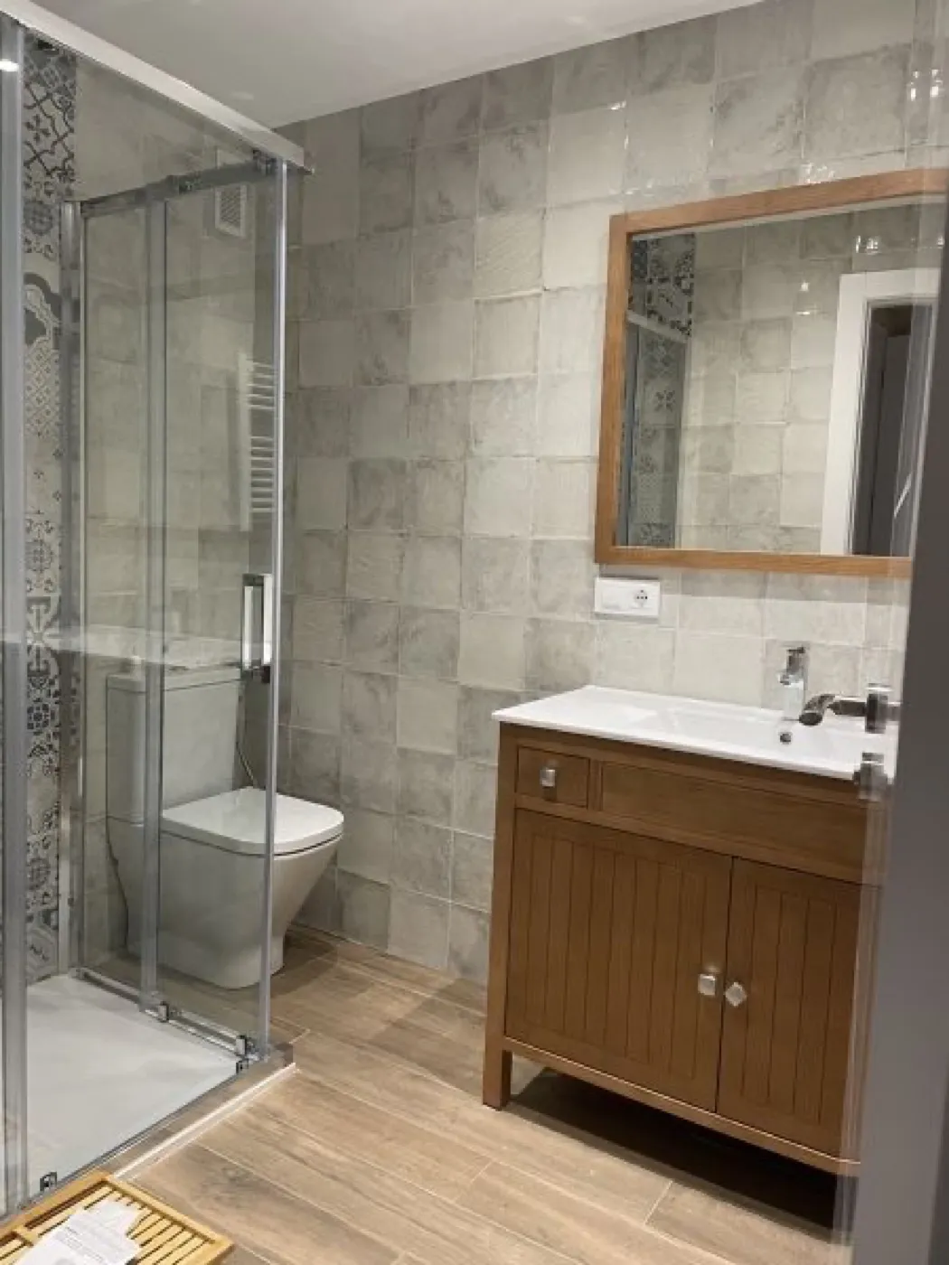 Baño con mueble de madera, mampara y azulejo decorado