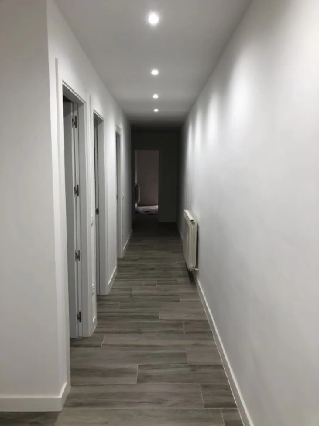 Pasillo reformado con luces empotradas y suelo porcelánico