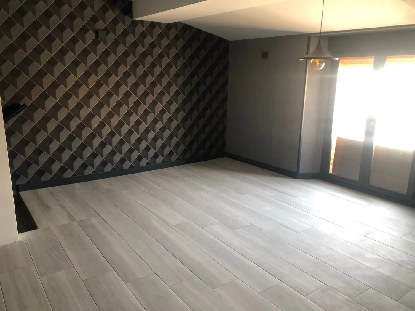 Salón con papel pintado geométrico y suelo porcelánico gris