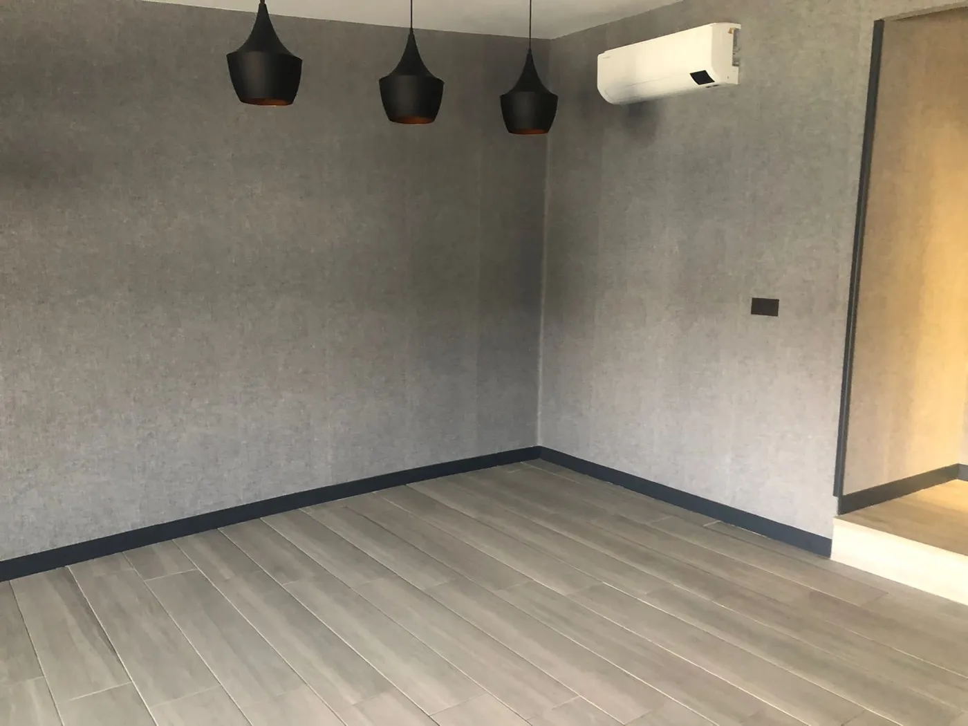 Salón con papel pintado gris, suelo porcelánico y aire acondicionado