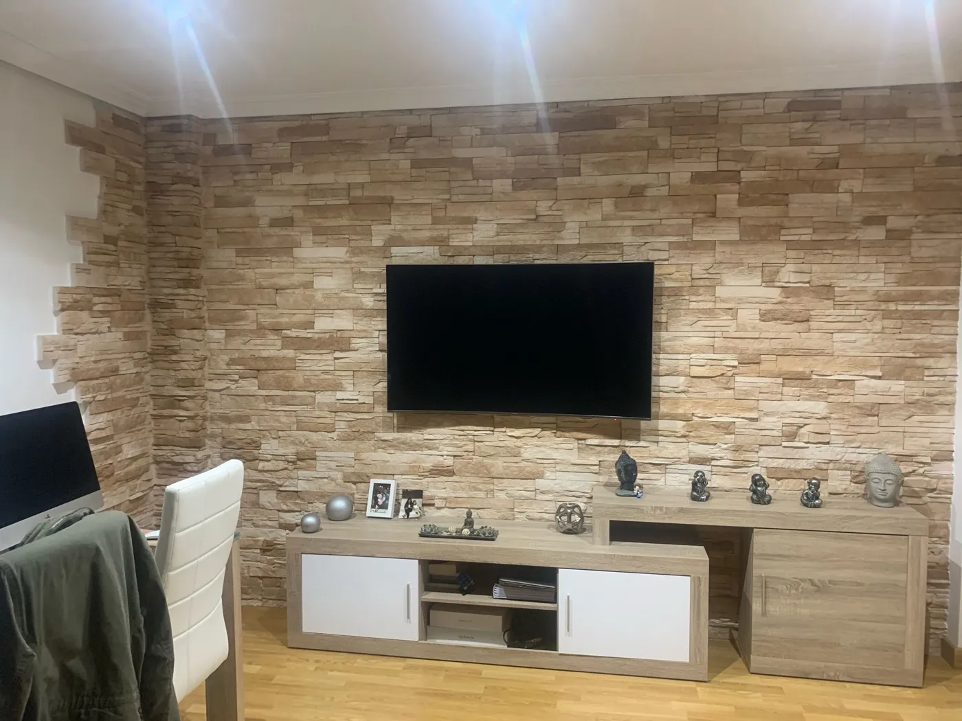 Salón reformado con pared revestida de piedra y mueble de TV a medida