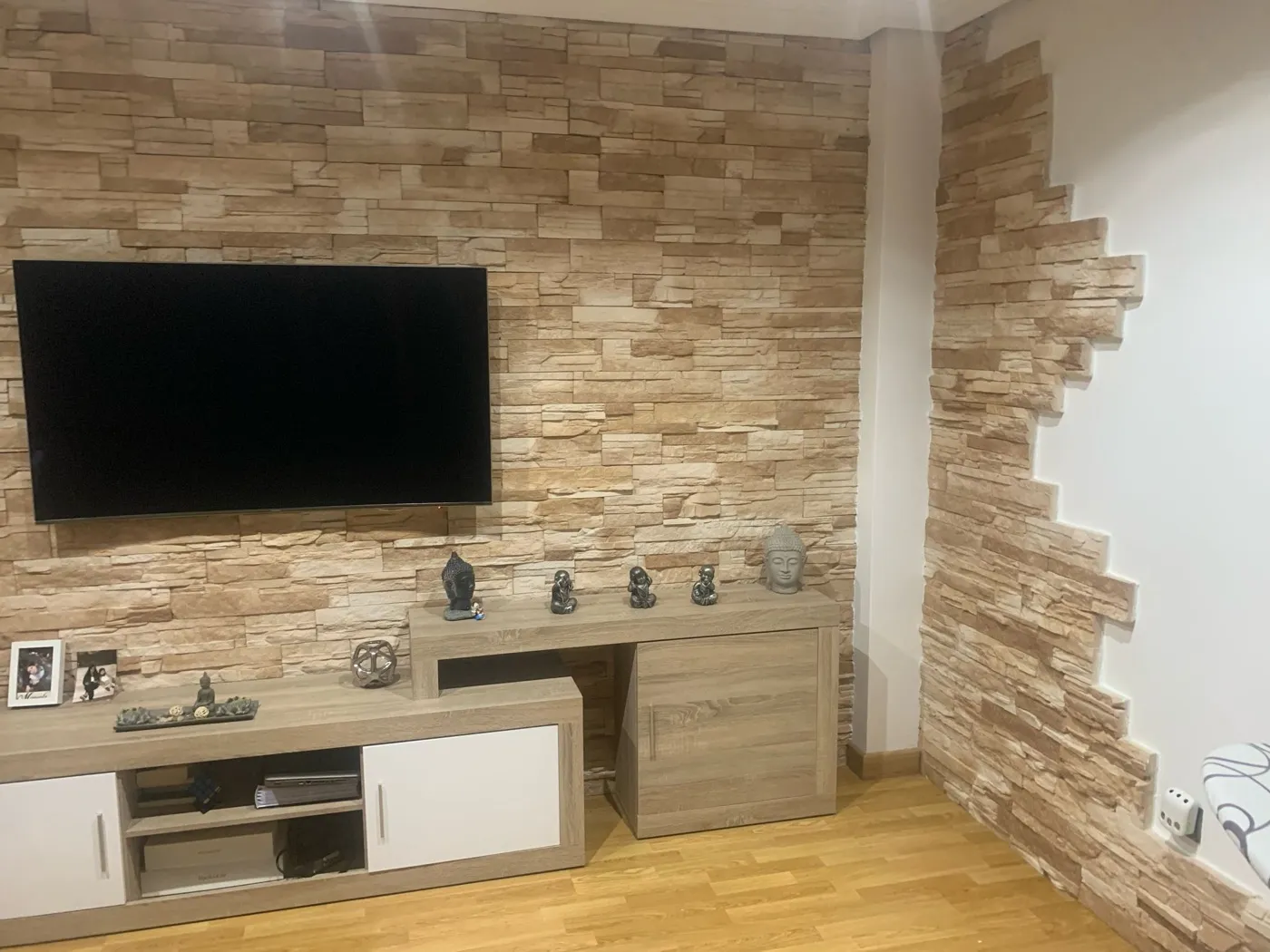 Salón amplio con pared de piedra y suelo de parqué
