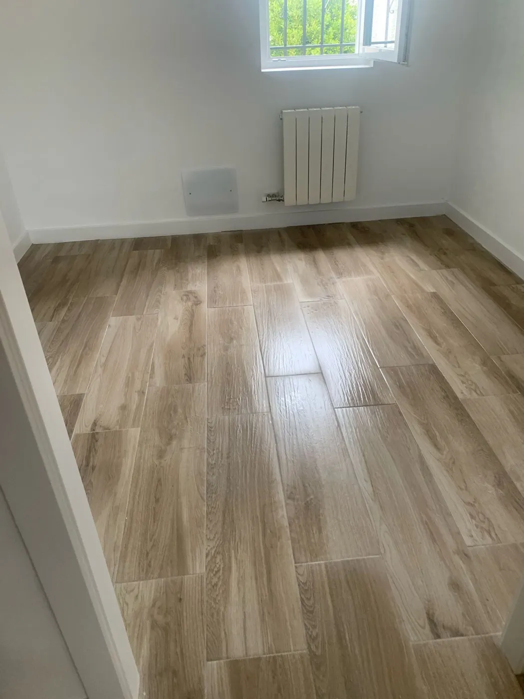 Habitación con suelo porcelánico imitación madera y radiador nuevo
